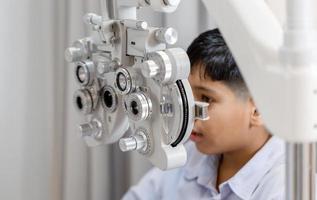 Junge, der Sehtests mit Optiker im Optikgeschäft durchführt, Optiker, der Sehtests für Kinderpatienten in der Klinik durchführt foto