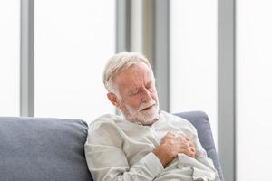 Nahaufnahme eines älteren Mannes mit Schmerzen im Herzen im Wohnzimmer, ein reifer Mann drückt die Hand auf die Brust, hat einen Herzinfarkt und leidet unter unerträglichen Schmerzen foto
