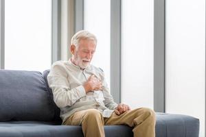 senior mann drückt hand auf brust hat herzinfarkt leidet unter unerträglichen schmerzen, mann mit herzschmerzen im wohnzimmer foto