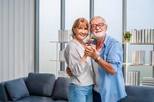 Porträt eines glücklichen älteren Paares, das im Wohnzimmer tanzt, einer älteren Frau und einem Mann, der tanzt, glückliche Familienkonzepte foto
