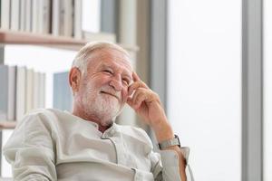 Porträt eines glücklichen Senioren, der sich im Wohnzimmer entspannt und genießt