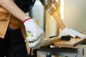 Tischler, der ein Maßband auf der Werkbank hält. Handwerker in einer Tischlerei foto