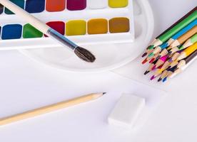 Buntstifte und Wasserfarben auf weißem Hintergrund. foto