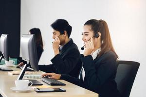 positives Lächeln junge asiatische Frau des Geschäftspersonals, die Kopfhörer und Computer verwendet. foto