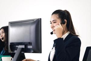 asiatische frau des jungen geschäftspersonals, die mit kopfhörern und computern zur unterstützung arbeitet. foto