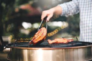 Mann Hand grillen Grill auf Feuer im Hinterhof am Tag foto