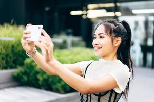 Junge asiatische Geschäftsfrau mit Handy für Online-Dating-App im Büro foto