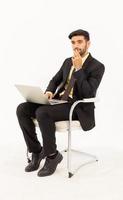 Ein hübscher männlicher Geschäftsmann sitzt idealerweise auf einem Stuhl und hat ein Tablet isoliert auf weißem Hintergrund, foto