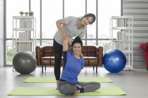 2 asiatische Frauen mittleren Alters, die in ihrem Haus Yoga auf einer Gummimatte machen. foto