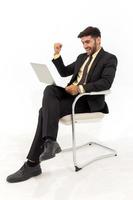 ein hübscher Geschäftsmann, der auf einem Stuhl sitzt und Anzeichen von Glück zeigt, isoliert auf weißem Hintergrund, foto