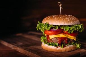 hausgemachter, frischer, leckerer Burger mit Salat und Käse auf rustikalem Holztisch. foto
