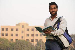 Indischer Student mit Büchern und Tasche auf dem College-Campus foto