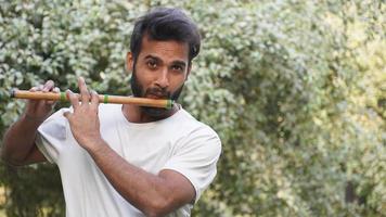 bansuri-spieler, der musik im sonnenschein im park-indischer flötenspieler spielt foto