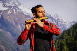 indischer mann, der indische flöte in den bergen spielt foto