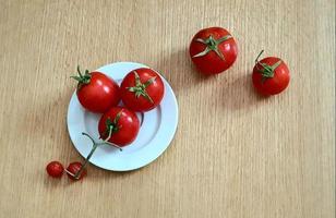 Einige frische Tomaten in einer weißen Schale auf einem Holzsockel foto