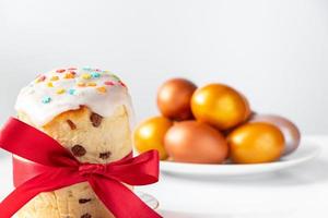 Osterkuchen mit süßem Zuckerguss und goldenen Eiern auf weißem Teller. foto