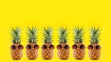 kreative ananas, die mit sonnenbrille und schale isoliert auf gelbem hintergrund nach oben schaut, sommerurlaub strandidee designmuster, kopierraum nah oben