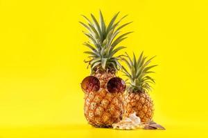 kreative ananas, die mit sonnenbrille und schale isoliert auf gelbem hintergrund nach oben schaut, sommerurlaub strandidee designmuster, kopierraum nah oben foto