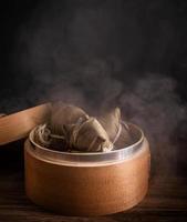 zongzi, gedämpfte reisknödel im dampfer auf holztisch, berühmtes leckeres essen im drachenbootfestival duanwu-designkonzept, nahaufnahme, kopierraum. foto