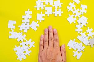 Puzzle und Hände auf dem gelben Konzepthintergrund foto