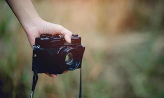 Hand und Kamera des Fotografen, der die Kamera hält und trägt, um Bilder aufzunehmen foto