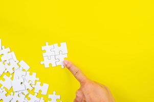 Puzzle und Hände auf dem gelben Konzepthintergrund foto