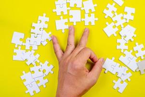 Puzzle und Hände auf dem gelben Konzepthintergrund foto