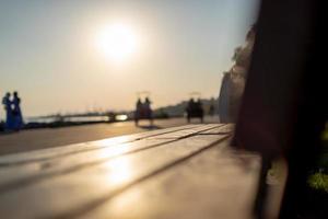 Holzsitzbank im Park und Silhouetten von Menschen mit Sonnenlicht foto