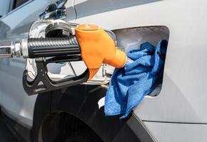 Eine orangefarbene Düse beim Tanken von Benzin in den Kraftstofftank des Autos an der Tankstelle. Tankstelle ist eine Einrichtung, die Kraft- und Schmierstoffe für Kraftfahrzeuge verkauft. foto