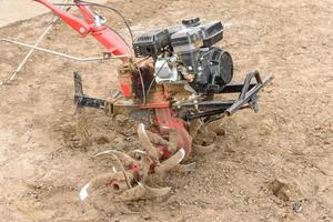 Ein kleiner Ackerschlepper pflügt den Boden, die Arbeit eines handgeführten Traktors foto