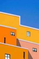 Manipulationstechniken für die Hintergrundgestaltung von architektonischen Merkmalen von farbenfrohen Gebäuden vor blauem, klarem Himmel in niedriger Winkelansicht und vertikalem Rahmen