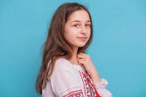 Mädchen auf blauem Hintergrund. Porträt eines 11-jährigen Mädchens in ukrainischer bestickter Kleidung. foto