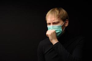 Mann mittleren Alters mit medizinischer Gesichtsmaske Porträt aus nächster Nähe veranschaulicht die pandemische Coronavirus-Krankheit auf dunklem Hintergrund. Covid-19-Ausbruchkontaminationskonzept. foto