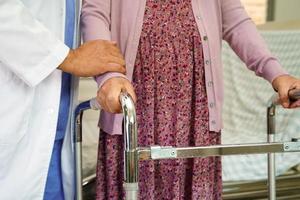 arzt hilft asiatischen älteren frauen mit behinderungspatienten zu fuß mit gehhilfe im pflegekrankenhaus, medizinisches konzept.