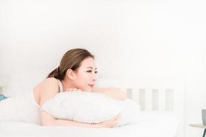 junges schönes asiatisches Mädchen mit langen Haaren, das auf einem weißen Bett schläft foto