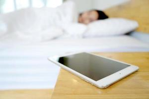 Schlafende Frau, die im Schlafzimmer per Handy geweckt wird foto