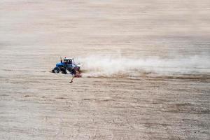 Seitenansicht des landwirtschaftlichen Industrietraktors pflügt Bodenfeld für die Aussaat, Luftbild. Landbewirtschaftung. foto