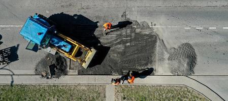 luftaufnahme von straßenarbeitern reparieren asphaltbelag. Teamwork-Konzept. Kontrast zwischen neuer und alter Fahrbahnoberfläche. foto