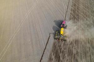 Traktor auf einem gepflügten Feld, Draufsicht. landwirtschaftliches Feld zum Anpflanzen von Gemüse. Traktor macht Furchen auf dem Feld. foto