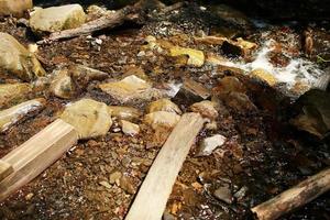 Fließender Bergbach mit transparentem Wasser und Steinen am Boden foto