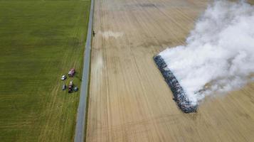 luftaufnahme von verbranntem land auf dem feld nach brand mit asche und rauch foto