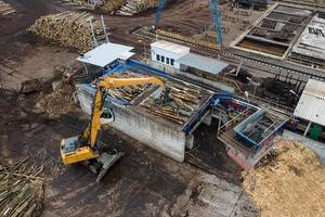 Ein Lader lädt Holzstämme in einer Holzverarbeitungsfabrik von oben von einer Drohne foto