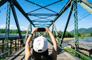 sie entspannt sich auf der historischen metallbrücke und nutzt das smartphone für soziale netzwerke. foto