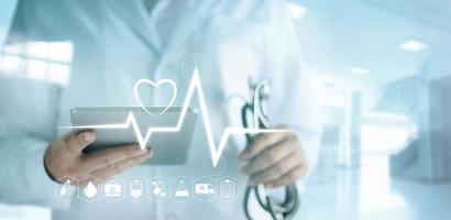 Arzt mit digitalem Tablet mit medizinischem Symbol und Herzschlagfrequenz im Krankenhaushintergrund