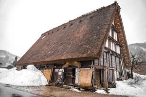 die dörfer shirakawago und gokayama gehören zu den unesco-welterbestätten japans. Bauernhaus im Dorf und Berg dahinter. foto