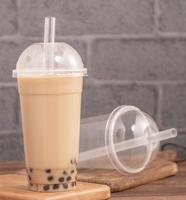 zum Mitnehmen mit Einwegartikel-Konzept beliebter taiwaner Getränk Bubble Milk Tea mit Plastikbecher und Strohhalm auf Holztischhintergrund, Nahaufnahme, Kopierraum foto