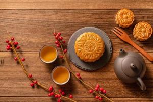 mondkuchen mondkuchen-tischdekoration - traditionelles chinesisches gebäck mit teetassen auf holzhintergrund, mittherbstfestkonzept, draufsicht, flache lage. foto