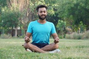 Attraktiver asiatischer Mann, der in Meditationshaltung sitzt, Yoga-Pranayama-Balance in der schönen Aussicht auf den Park während des Sonnenuntergangs. Gesundheits- und Wellness- und Fitnesskonzept foto