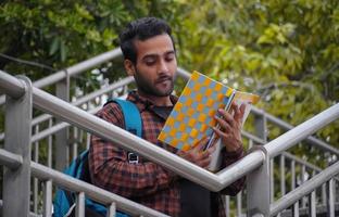 Student mit Büchern stellt einen Jungen in der Nähe des College-Campus mit seinem Buch und seinen Taschen dar und verwirrt ihn