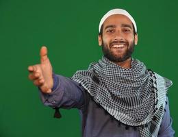 muslimischer junge, der seine hand für hilfe hält, schüttelt auf grünem bildschirmhintergrund. foto